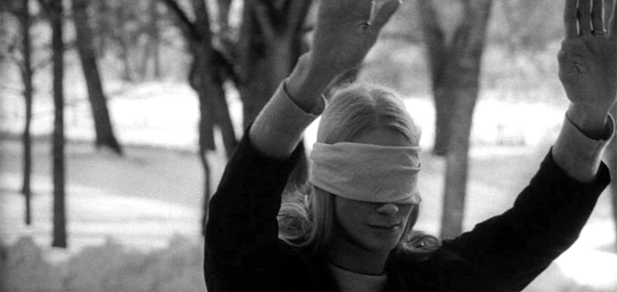 Ingrid Thulin as Irene, blindfolded with her arms out in a forest in a still from Night Games (1966)