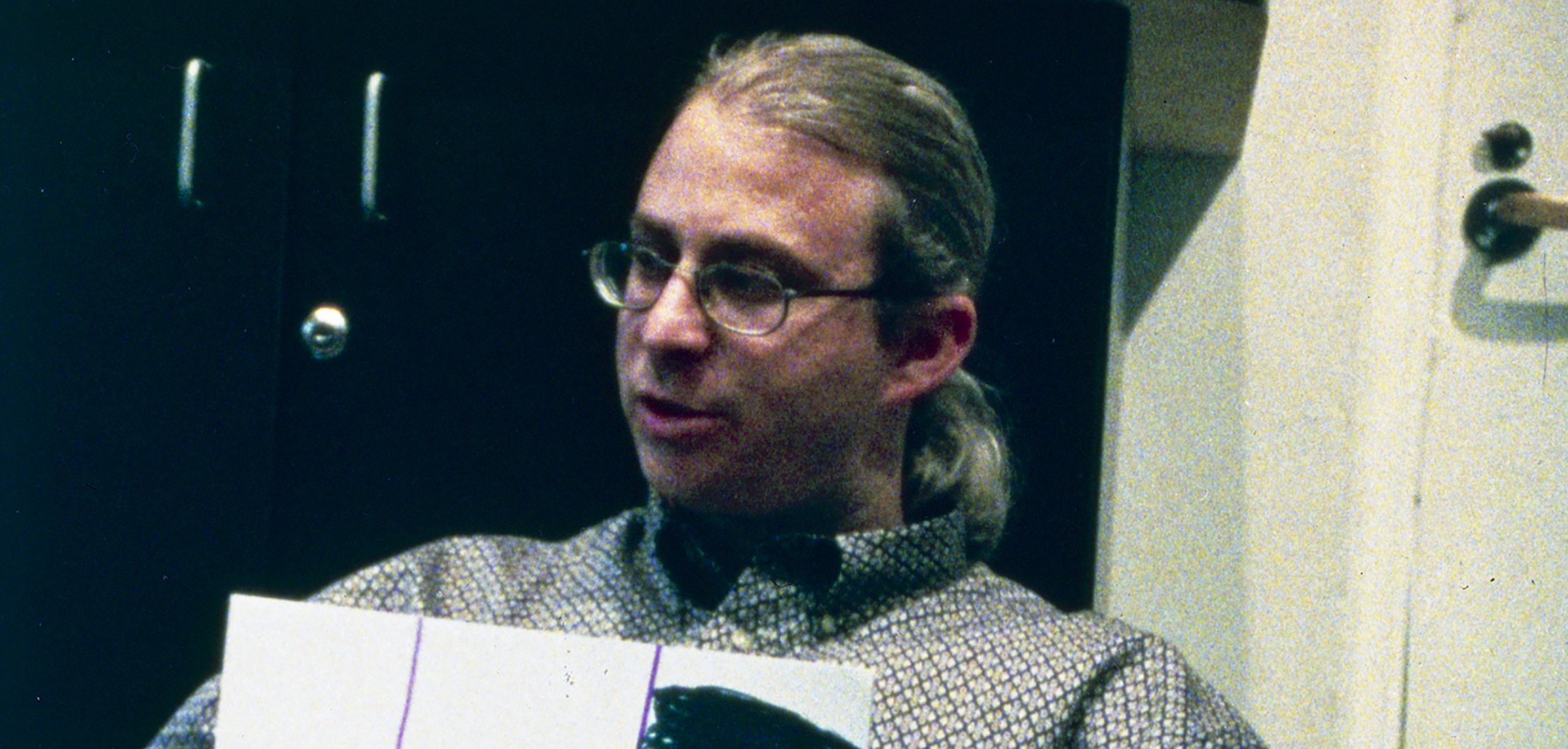 Headshot of a social worker with a ponytail and wearing glasses in a still from 'Domestic Violence' (2001) Zipporah Films, Inc.