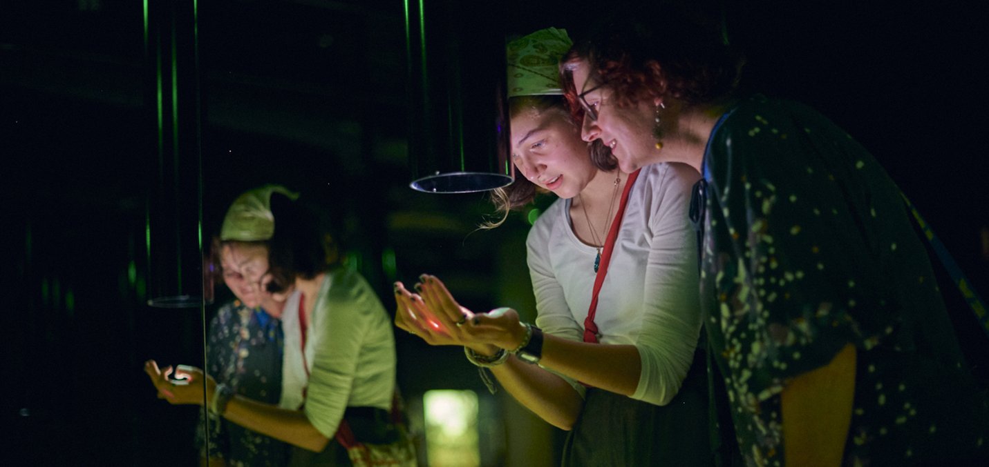 A woman and her daughter look at videos projected on their hands in the Memory Garden at ACMI - Eugene Hyland