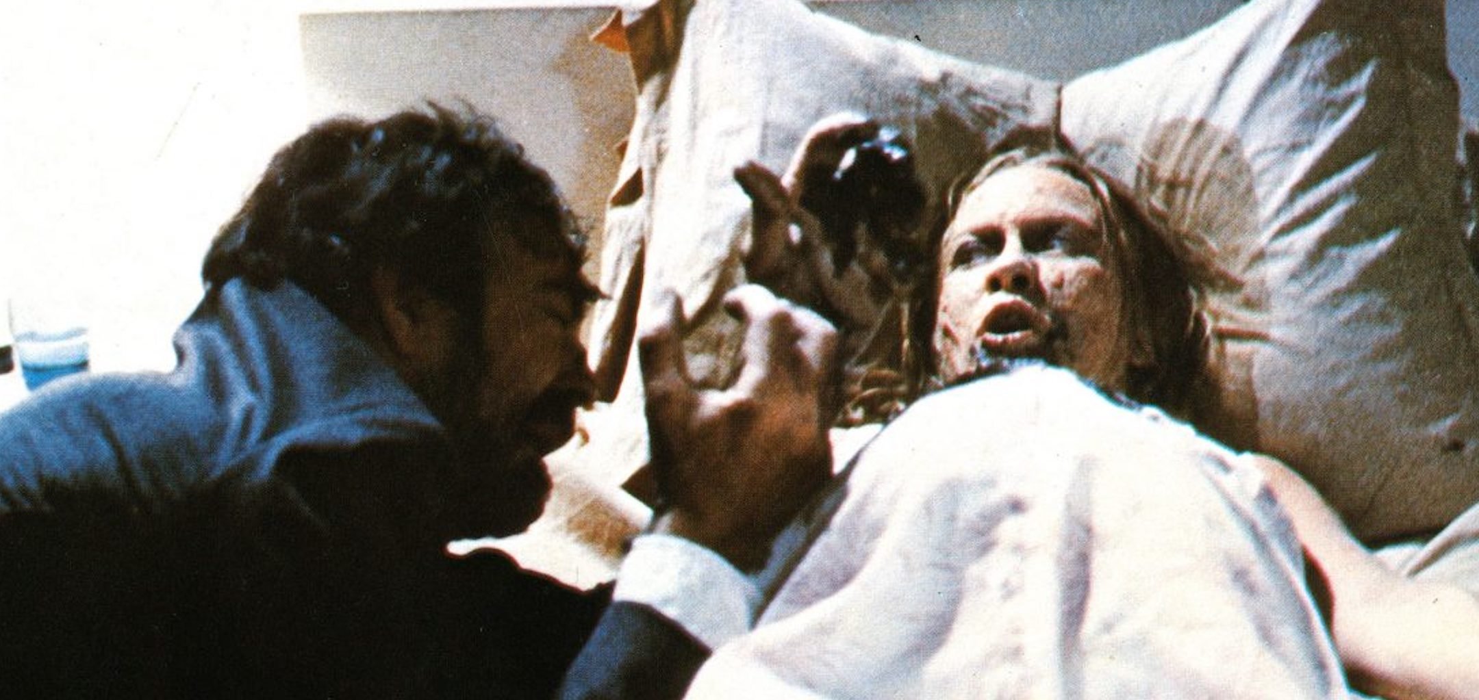 A man performs an exorcism on a terrified woman in bed
