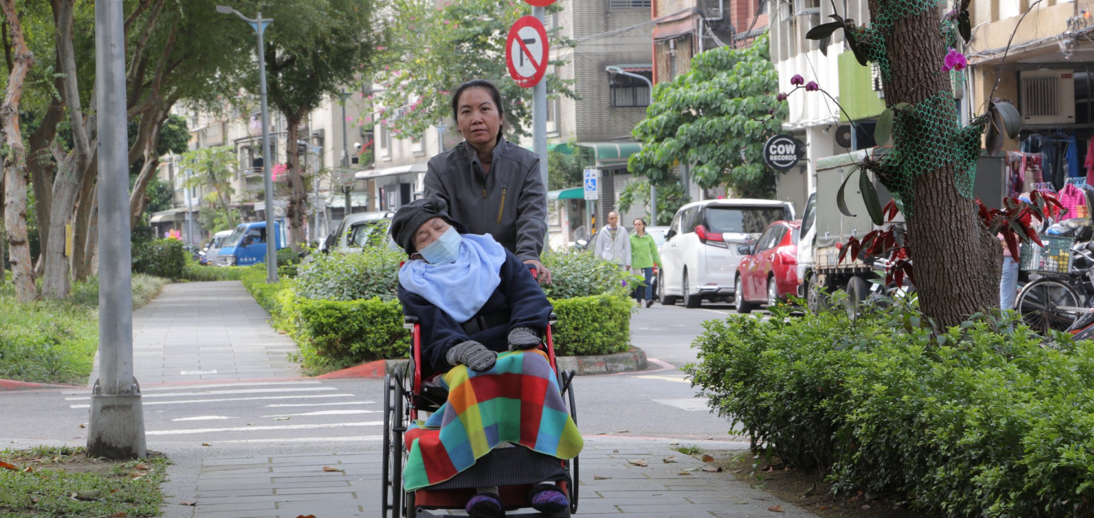 An Indonesian woman pushes an elderly person in a wheelchair in a still from 'Help is on the Way' - IFF 2021