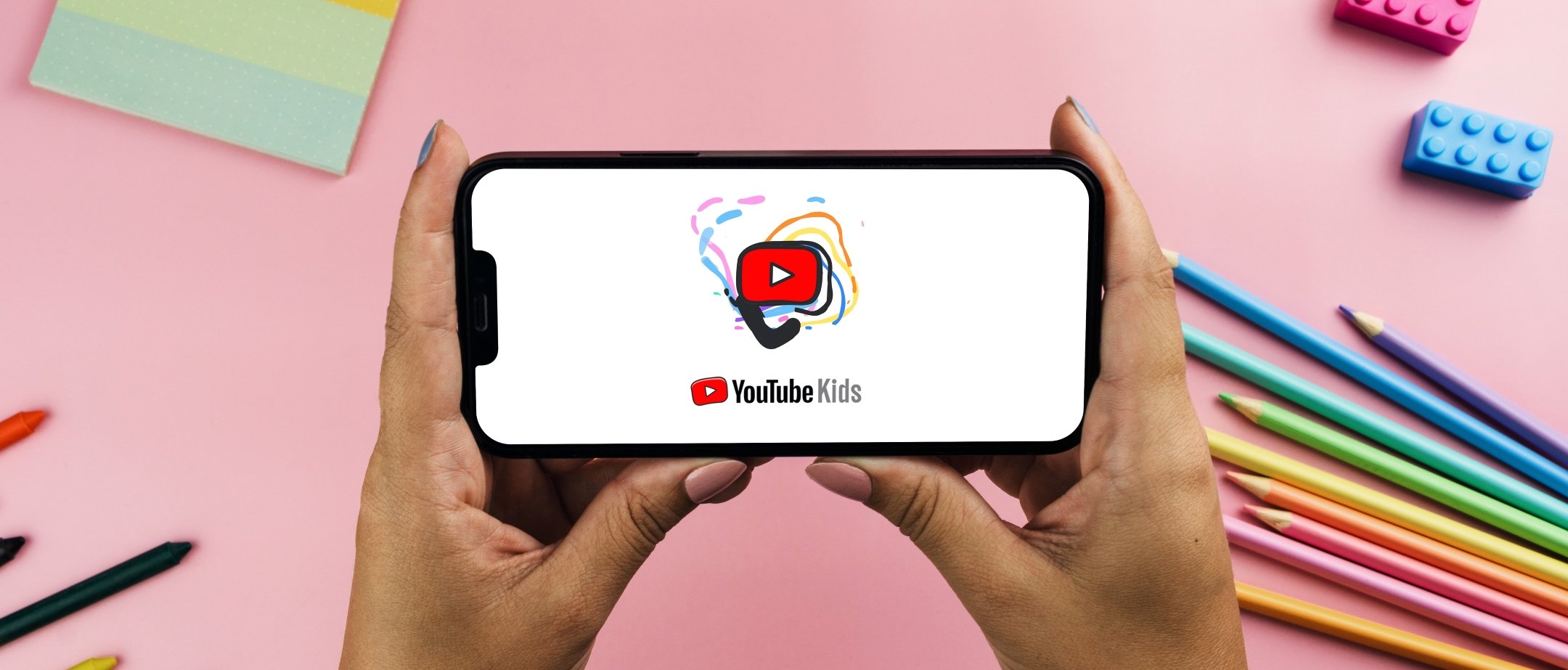 A pair of hands holding a smartphone sideways with the YouTube icon on it.