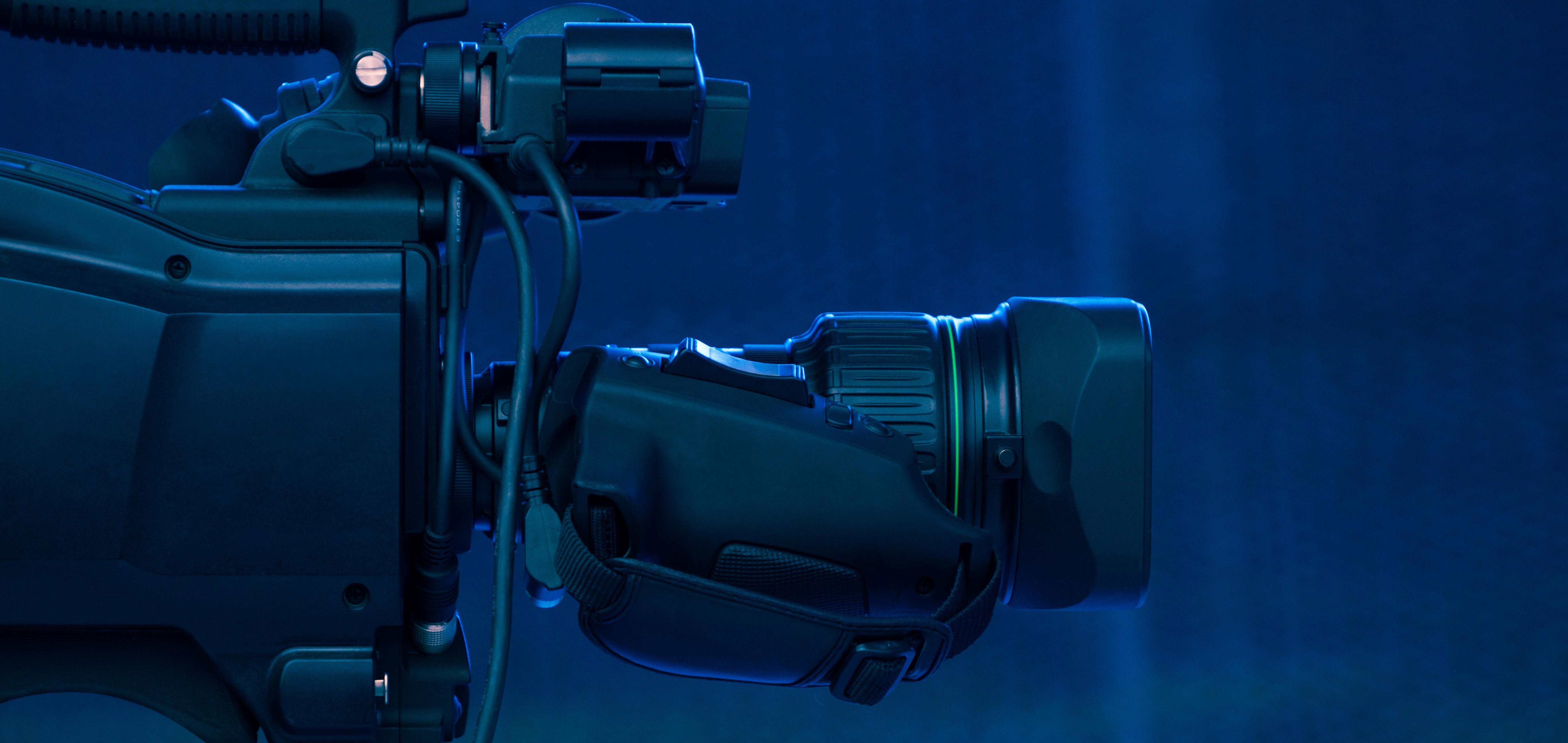 Side view of a black video camera on a blue background