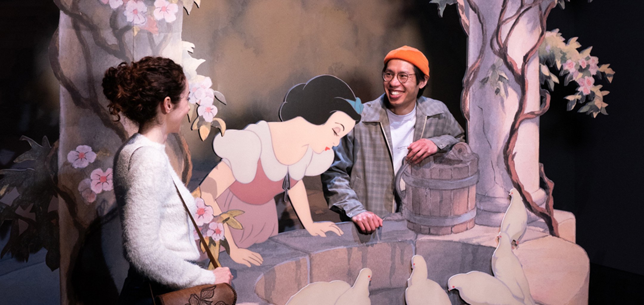 Two people interacting with the Wishing Well in the Disney - The Magic of Animation exhibition